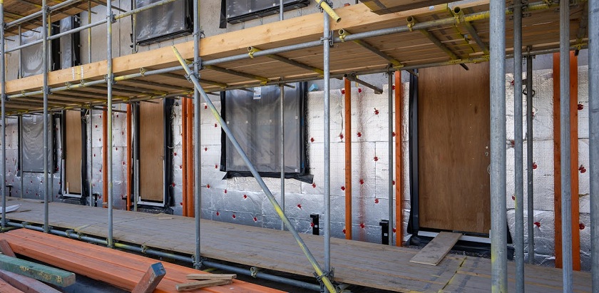 Baustelle/Neubau eines Hauses, vor dem ein Baugerüst steht. 